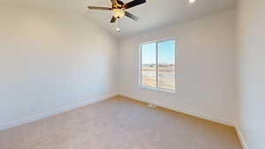 Spare room with light colored carpet, ceiling fan, and lofted ceiling