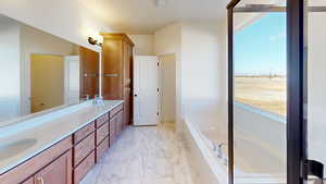 Bathroom with tiled bath, a wealth of natural light, and vanity