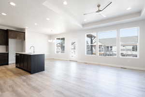 Kitchen featuring dark brown cabinetry, sink, light wood-type flooring, and a wealth of natural light