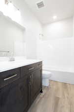 Full bathroom featuring vanity, shower / tub combination, wood-type flooring, and toilet