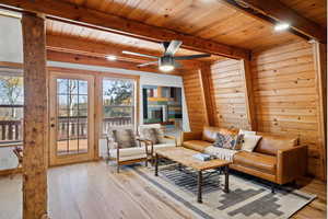 Sitting room with light hardwood / wood-style floors, wood ceiling, beam ceiling, and ceiling fan