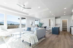 Living room with a mountain view, hardwood / wood-style flooring, a tray ceiling, and ceiling fan