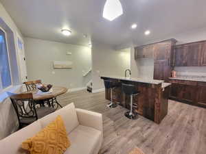 Bar featuring light hardwood / wood-style floors, light stone counters, and dark brown cabinetry