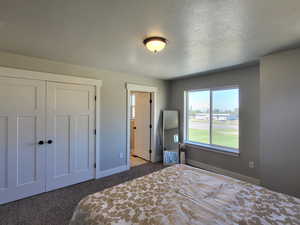 Carpeted bedroom featuring a textured ceiling and a closet