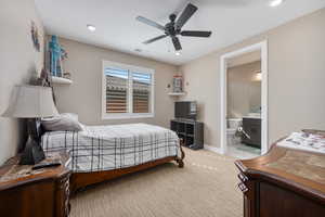 Carpeted bedroom featuring connected bathroom and ceiling fan