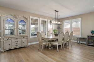 Dining space featuring a healthy amount of sunlight, light hardwood / wood-style flooring, a chandelier, and beverage cooler