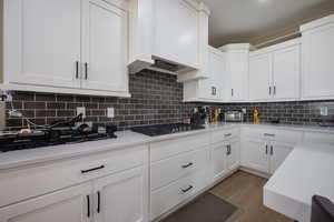 Kitchen with white cabinets, light hardwood / wood-style floors, and tasteful backsplash