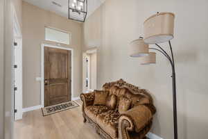 Foyer featuring an inviting chandelier, a high ceiling, and light wood-type flooring