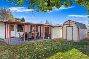 Back of house with a storage shed, a yard, and a patio