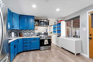 Kitchen featuring blue cabinetry, stainless steel appliances, and light hardwood / wood-style floors