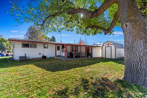 Rear view of house featuring a patio, a storage shed, a yard, and central AC unit