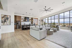 Living room featuring ceiling fan with notable chandelier and light wood-type flooring