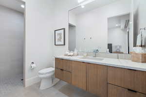 Bathroom with vanity, a tile shower, toilet, and tile patterned floors