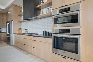 Kitchen with light hardwood / wood-style flooring, tasteful backsplash, stainless steel appliances, and light brown cabinetry