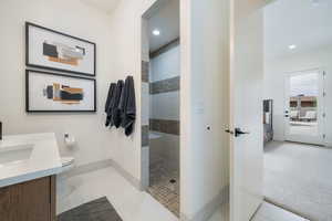 Bathroom featuring vanity, tiled shower, toilet, and tile patterned floors