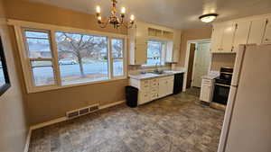 Kitchen featuring white cabinets, white fridge, stainless steel range, and a healthy amount of sunlight