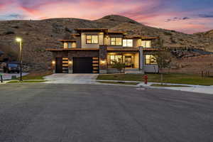 View of front of property with a mountain view, a yard, and a garage