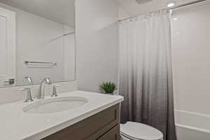 Full bathroom with vanity, shower / tub combo with curtain, and toilet