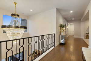 Hall with a notable chandelier, a healthy amount of sunlight, and dark hardwood / wood-style flooring