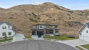 View of front of house featuring a garage, a mountain view, and a front lawn