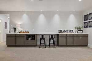 Bar with light carpet and gray cabinetry