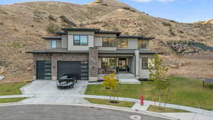 View of front facade with a garage, a trampoline, a mountain view, and a front lawn