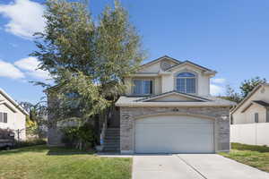 View of front of home with a garage and a front lawn