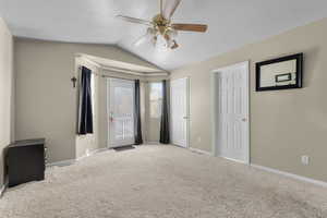 Unfurnished bedroom featuring ceiling fan, a textured ceiling, lofted ceiling, and light colored carpet