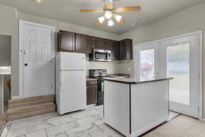 Kitchen featuring black range with electric cooktop, a kitchen island, dark brown cabinets, ceiling fan, and white fridge