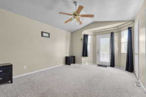 Carpeted spare room with a textured ceiling, ceiling fan, and vaulted ceiling