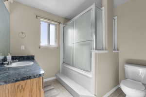 Full bathroom with vanity, toilet, and combined bath / shower with glass door