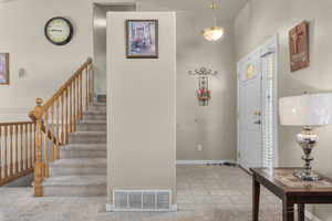 Carpeted foyer featuring vaulted ceiling