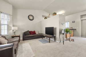 Living room featuring vaulted ceiling and light colored carpet