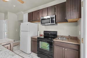 Kitchen with sink, dark brown cabinetry, black electric range, white fridge, and ceiling fan