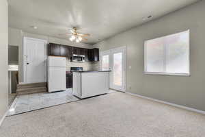 Kitchen with white fridge, light carpet, and dark brown cabinets