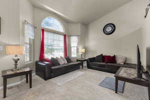 Carpeted living room with high vaulted ceiling