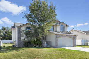 View of front of property featuring central AC, a front lawn, and a garage