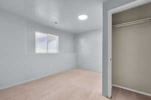 Unfurnished bedroom featuring a closet and light colored carpet