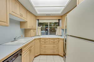 Kitchen with light brown cabinetry, appliances with stainless steel finishes, sink, and light tile patterned floors