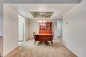 Dining space featuring a notable chandelier and light colored carpet