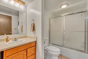 Full bathroom featuring vanity, combined bath / shower with glass door, and toilet