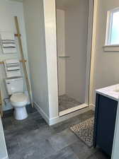 Bathroom featuring vanity, tiled shower, and toilet