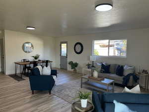 Living room with light hardwood / wood-style floors and a textured ceiling