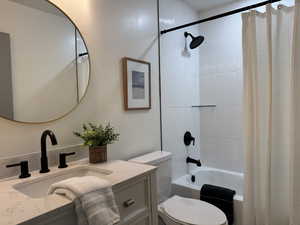 Full bathroom with vanity, toilet, and shower / bathtub combination with curtain