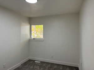 Unfurnished room featuring dark colored carpet