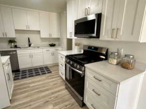 Kitchen featuring light hardwood / wood-style flooring, white cabinetry, stainless steel appliances, and sink