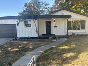 View of front of house featuring a porch, a front lawn, and a garage