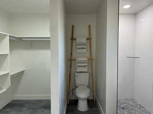 Bathroom with toilet, walk in shower, and tile patterned floors