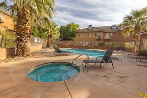 View of pool with a hot tub and a patio area