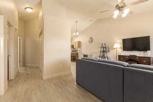 Living room featuring high vaulted ceiling, ceiling fan with notable chandelier